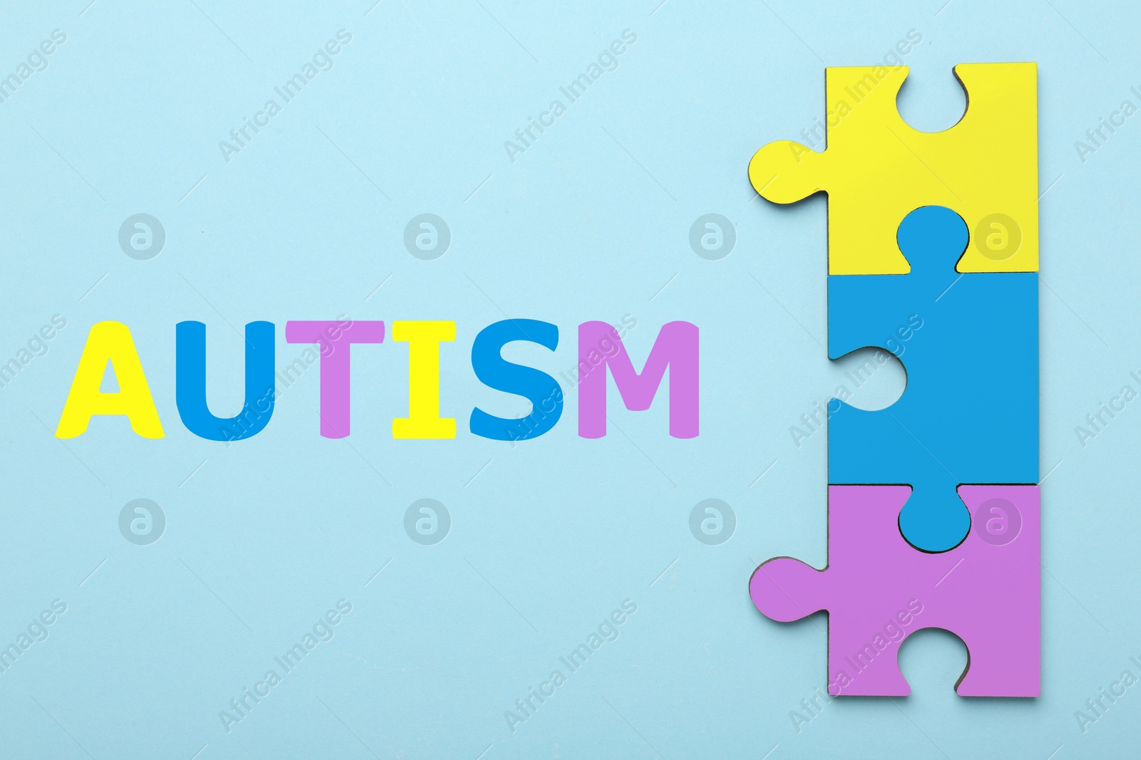 Image of Autism word and colorful puzzle pieces on light blue background, top view