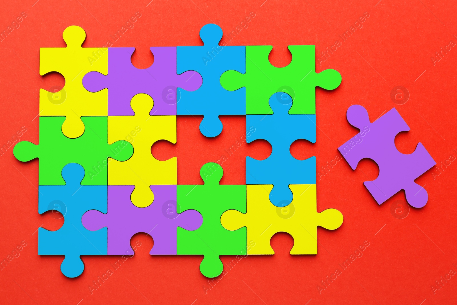 Image of Many colorful puzzle pieces on red background, top view. Symbol of autism