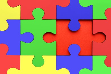 Image of Many colorful puzzle pieces on red background, top view. Symbol of autism