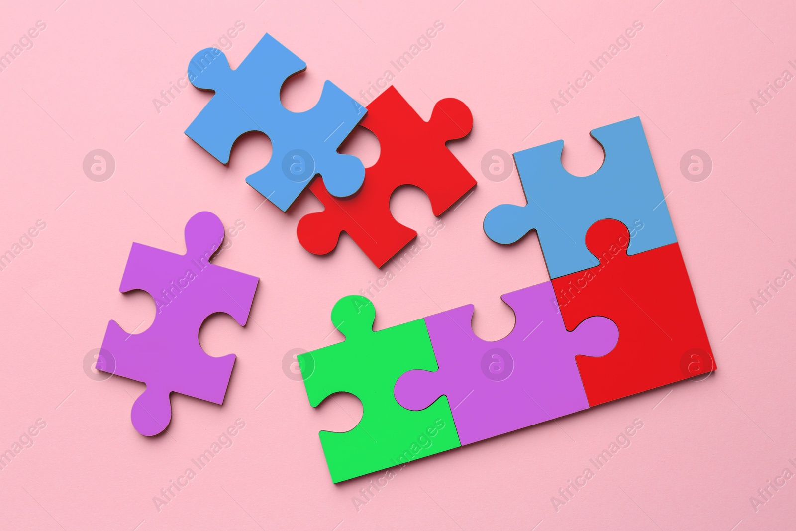 Image of Many colorful puzzle pieces on pink background, top view. Symbol of autism