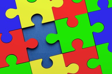 Image of Many colorful puzzle pieces on blue background, top view. Symbol of autism