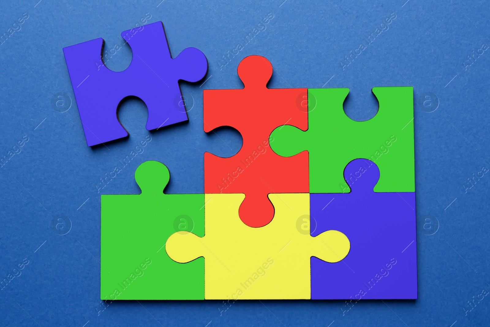 Image of Many colorful puzzle pieces on blue background, top view. Symbol of autism