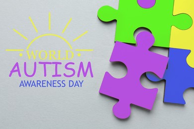 Image of World Autism Awareness Day text and colorful puzzle pieces on light grey background, top view