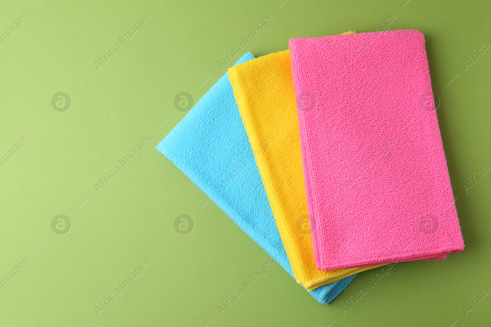 Photo of Different microfiber cloths on green background, top view. Space for text