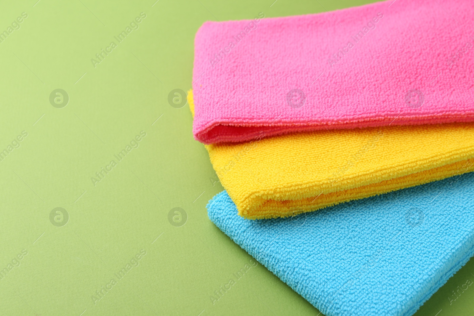 Photo of Different microfiber cloths on green background, closeup. Space for text