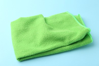 Photo of Clean green microfiber cloth on light blue background, closeup