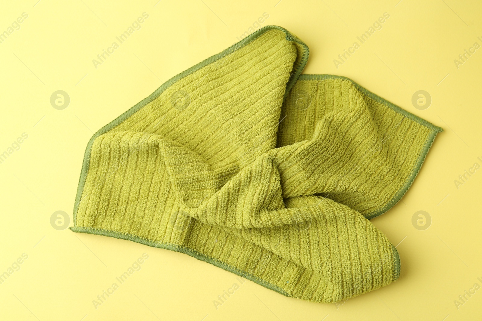 Photo of Clean green microfiber cloth on yellow background, top view