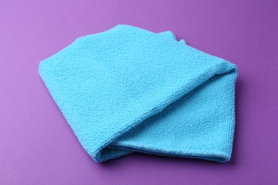 Clean light blue microfiber cloth on purple background, closeup