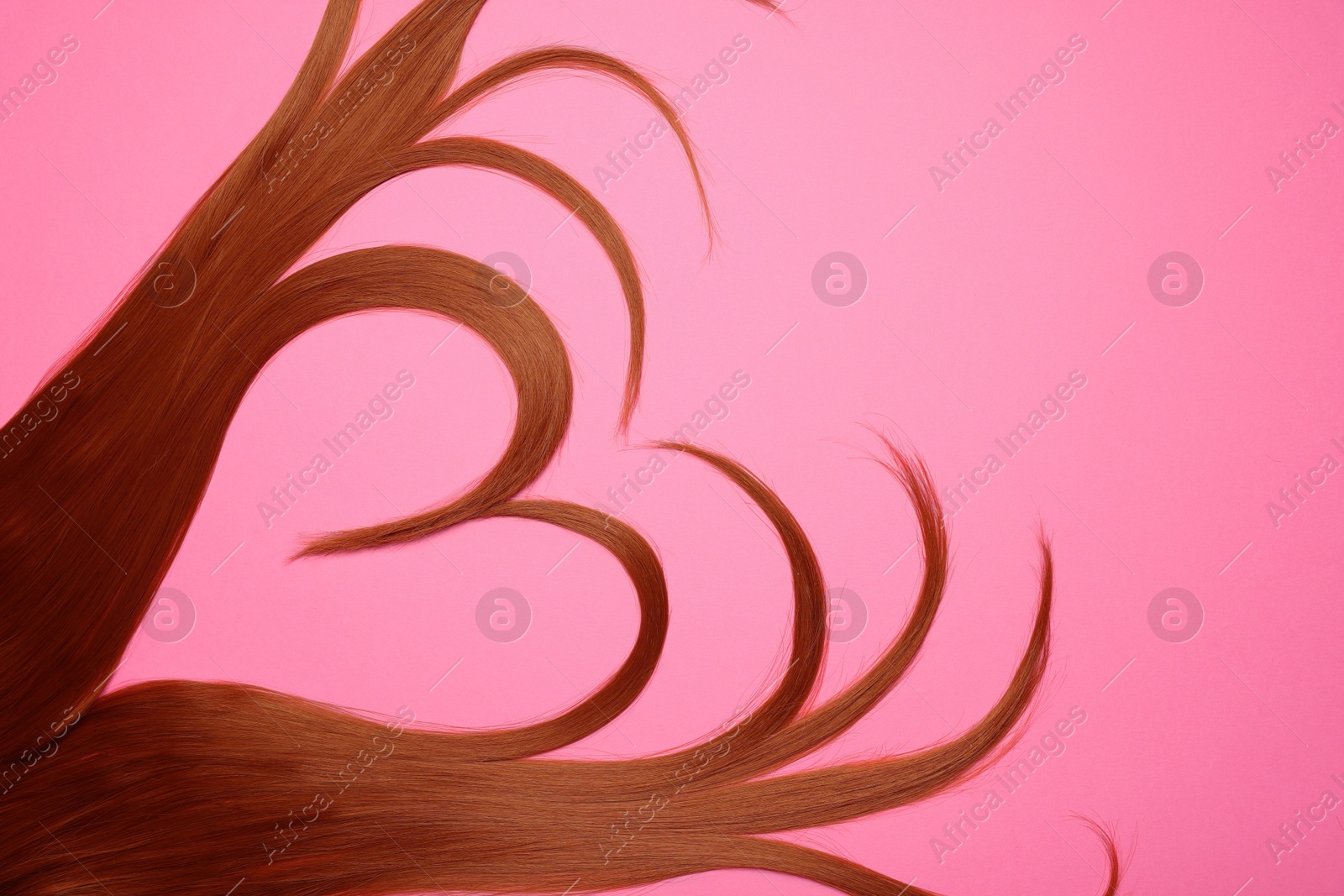 Photo of Red hair strands in shape of heart on pink background, top view. Space for text