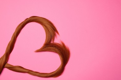 Photo of Red hair strands in shape of heart on pink background, top view. Space for text