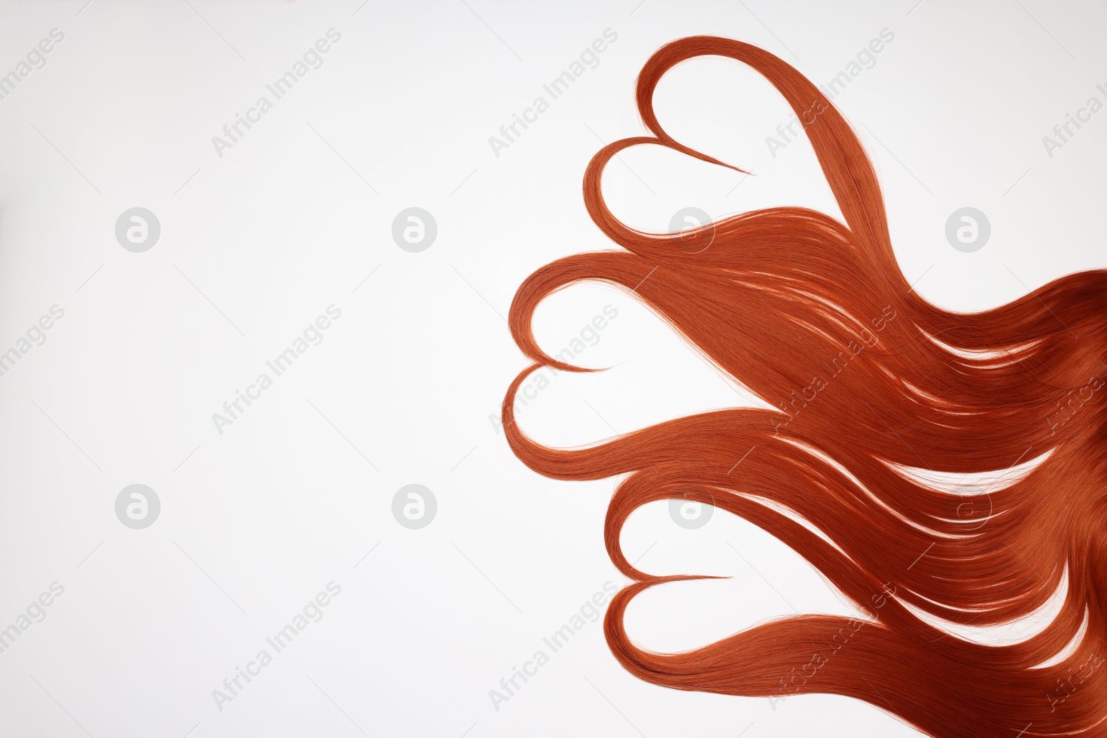 Photo of Red hair strands in shape of hearts on white background, top view. Space for text