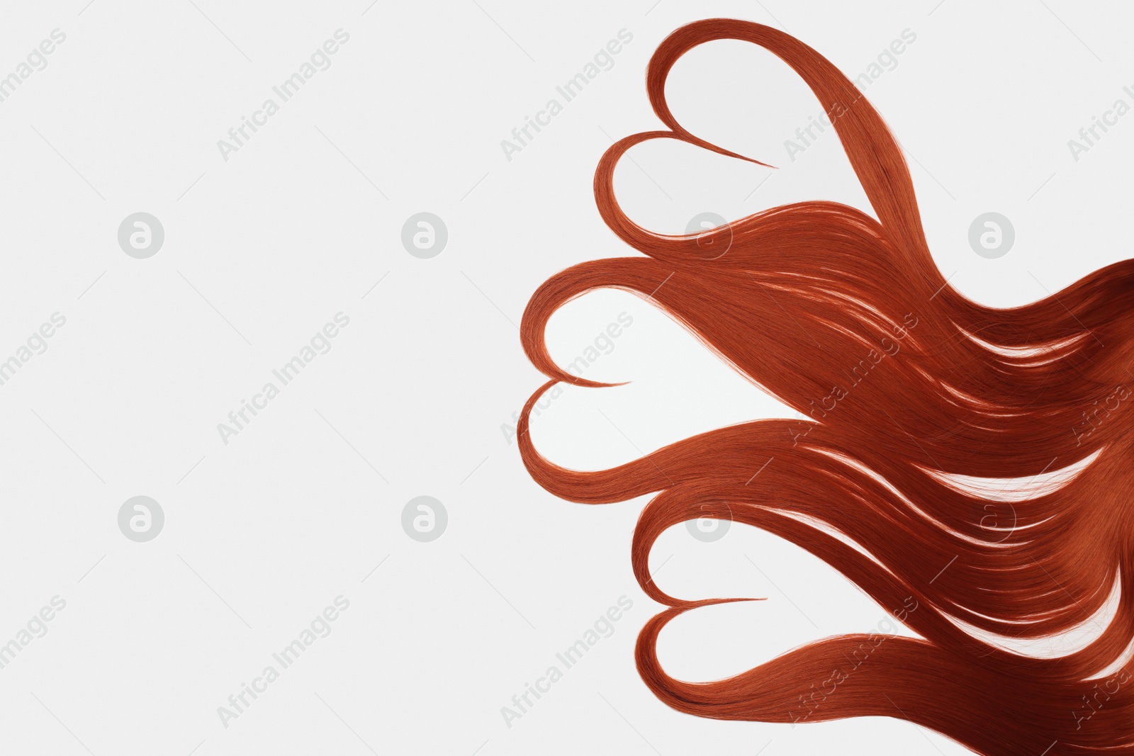 Photo of Red hair strands in shape of hearts on white background, top view. Space for text