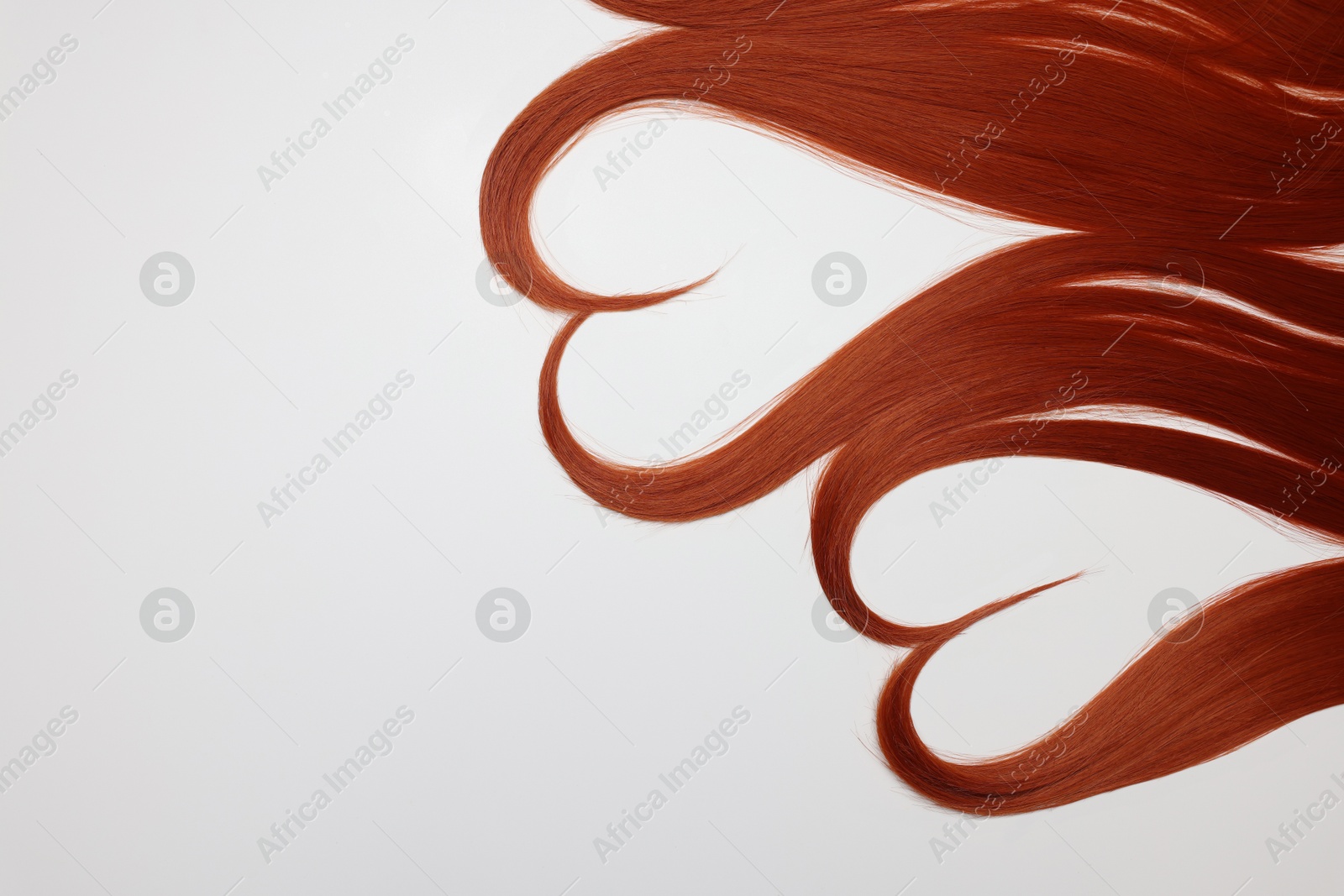 Photo of Red hair strands in shape of hearts on white background, top view. Space for text