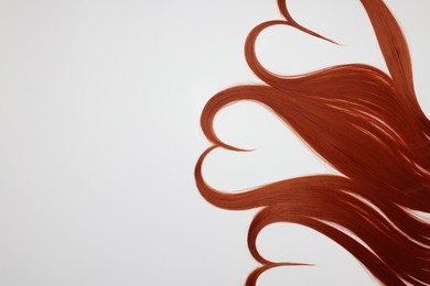 Photo of Red hair strands in shape of hearts on white background, top view. Space for text