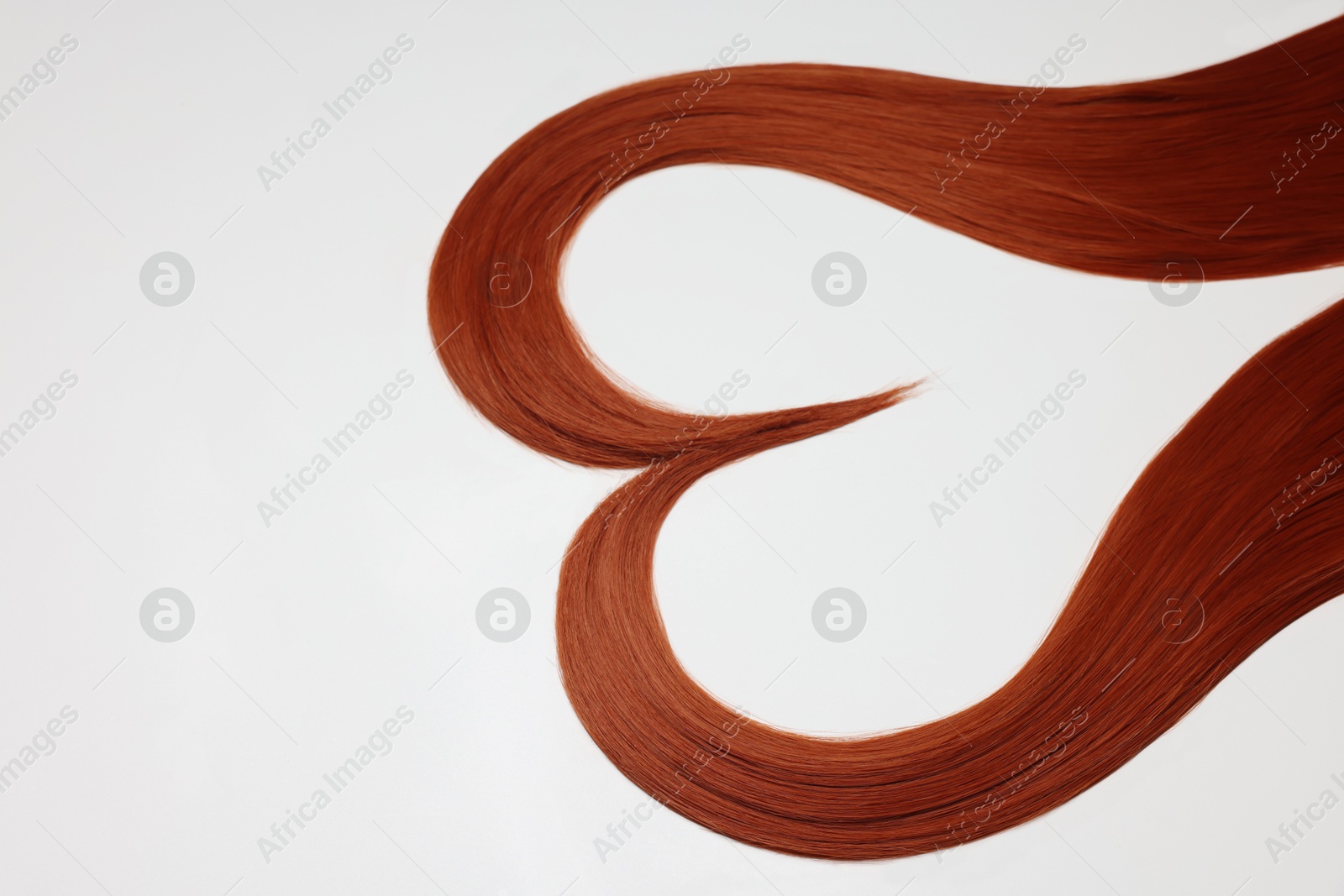 Photo of Red hair strands in shape of heart on white background, above view. Space for text