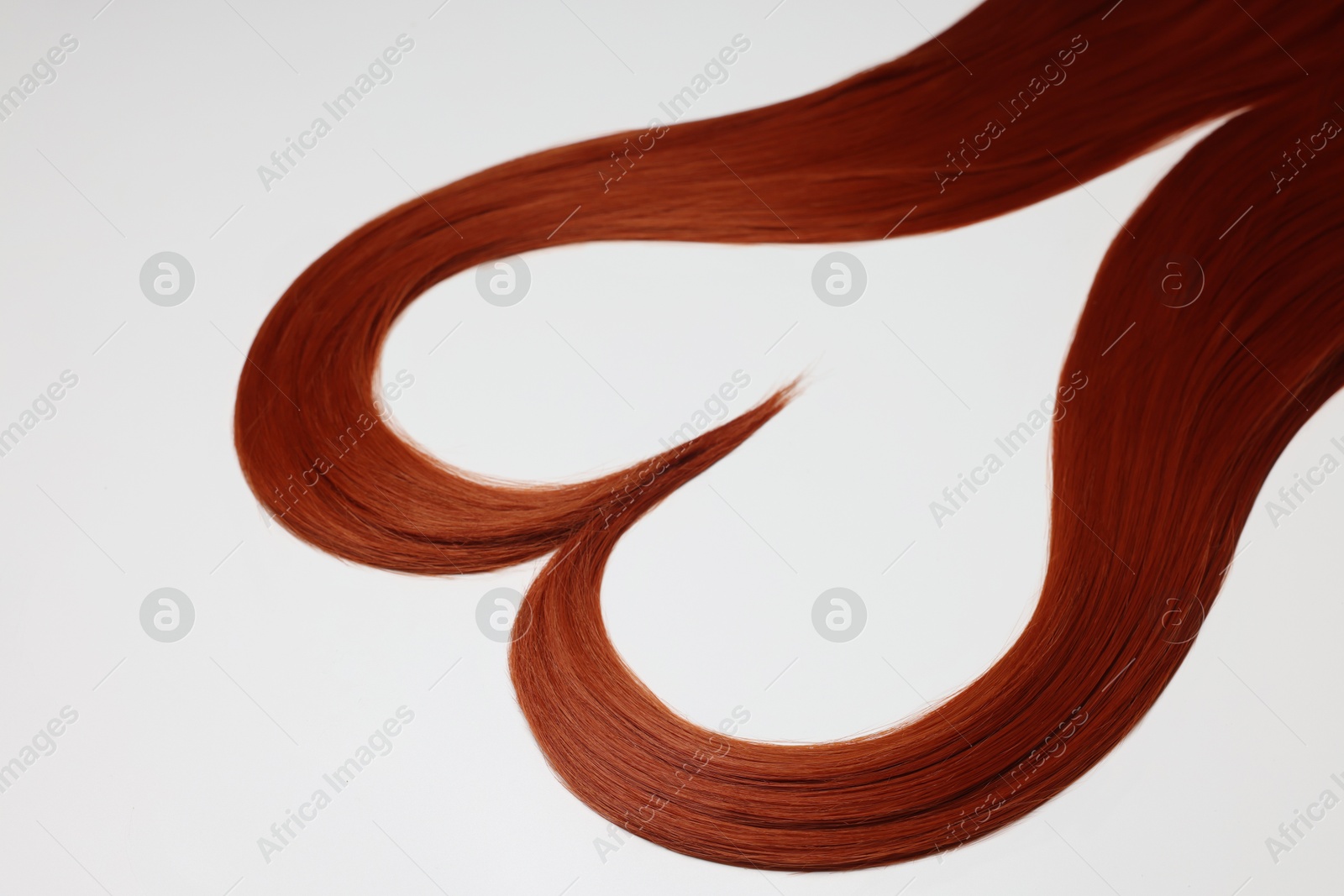 Photo of Red hair strands in shape of heart on white background, closeup