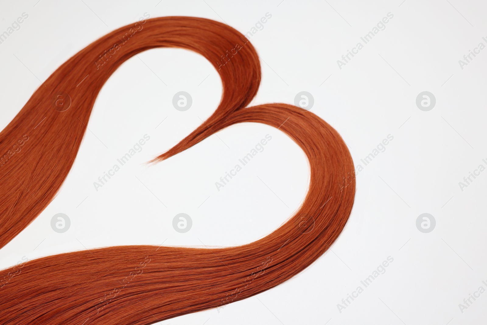 Photo of Red hair strands in shape of heart on white background, closeup