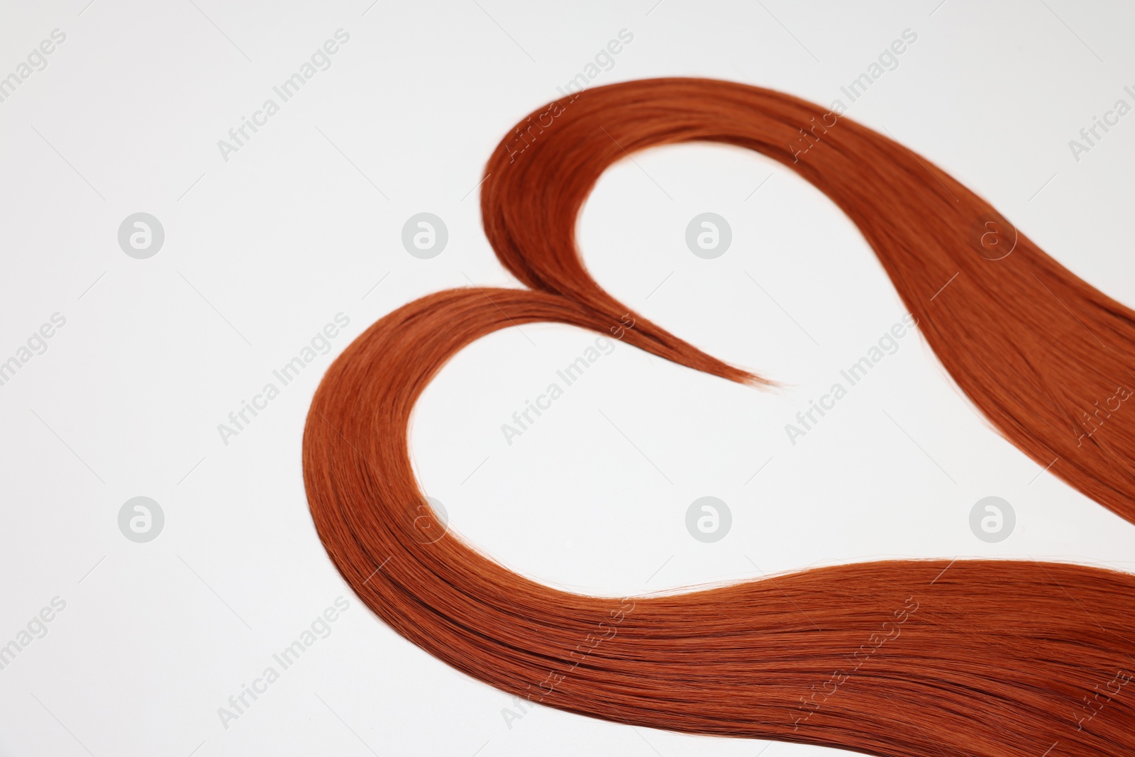 Photo of Red hair strands in shape of heart on white background, closeup