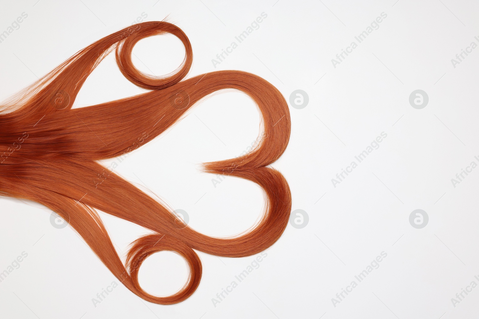 Photo of Red hair strands in shape of heart on white background, top view. Space for text