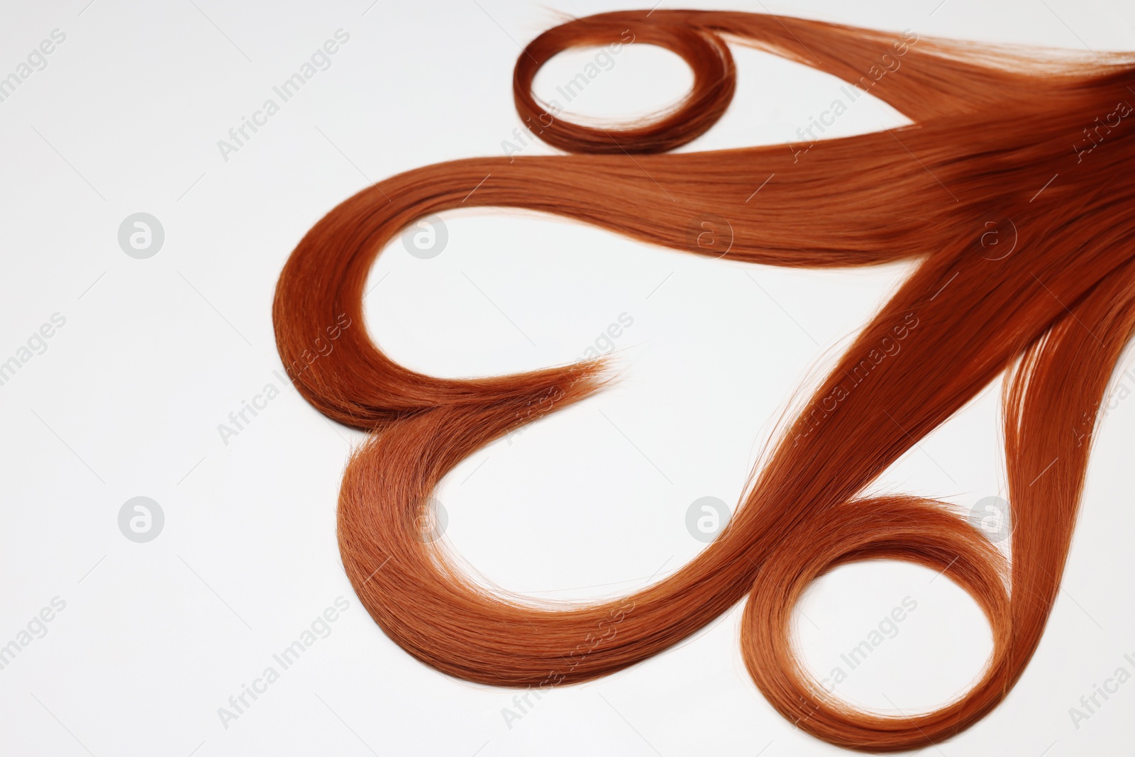 Photo of Red hair strands in shape of heart on white background, closeup