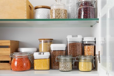 Different types of cereals and legumes in containers in closet