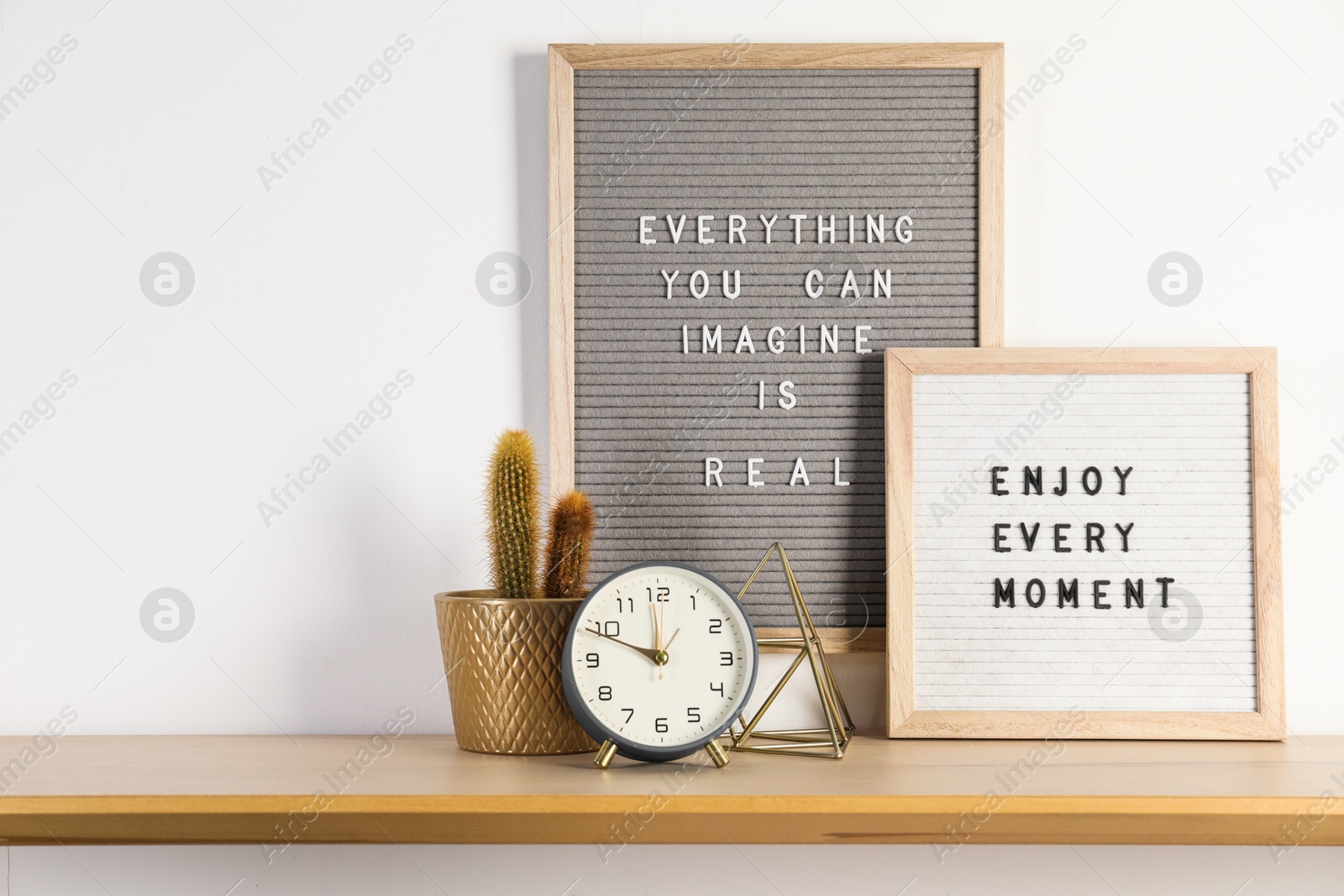 Photo of Letter boards with phrases Everything You Can Imagine Is Real, Enjoy Every moment and decor elements on wooden table