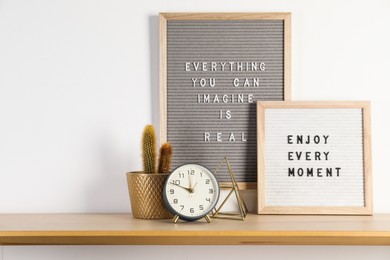 Photo of Letter boards with phrases Everything You Can Imagine Is Real, Enjoy Every moment and decor elements on wooden table