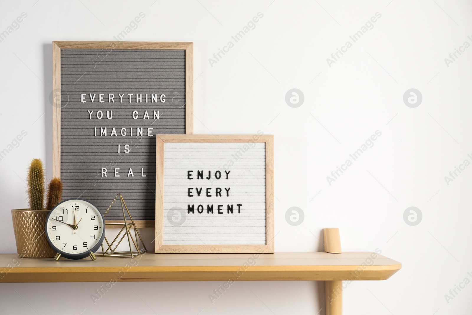 Photo of Letter boards with phrases Everything You Can Imagine Is Real, Enjoy Every moment and decor elements on wooden table