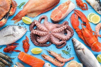 Different sea food on light blue wooden table, flat lay