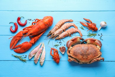 Different sea food on light blue wooden table, flat lay