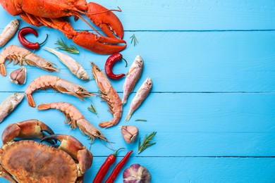 Different sea food on light blue wooden table, flat lay. Space for text