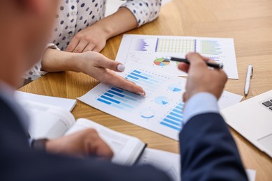 Photo of Banker working with client at wooden table in office, closeup