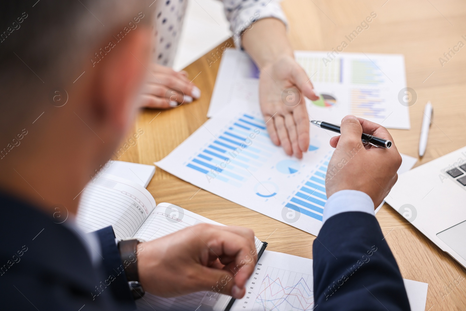 Photo of Banker working with client at wooden table in office, closeup