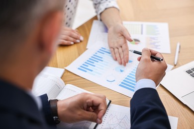 Banker working with client at wooden table in office, closeup