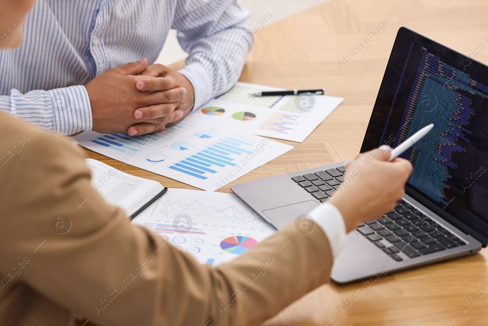 Photo of Banker working with client at wooden table in office, closeup