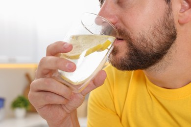 Man drinking water with lemon indoors, closeup