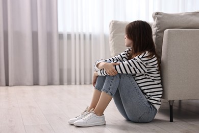 Photo of Loneliness concept. Sad teenage girl on floor at home, space for text