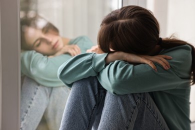 Photo of Loneliness concept. Sad teenage girl near window at home