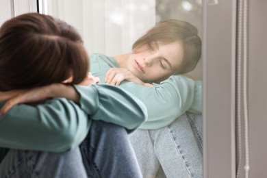 Loneliness concept. Sad teenage girl near window at home