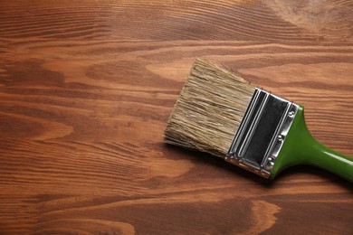 Photo of Applying walnut wood stain. Brush on wooden surface, top view. Space for text