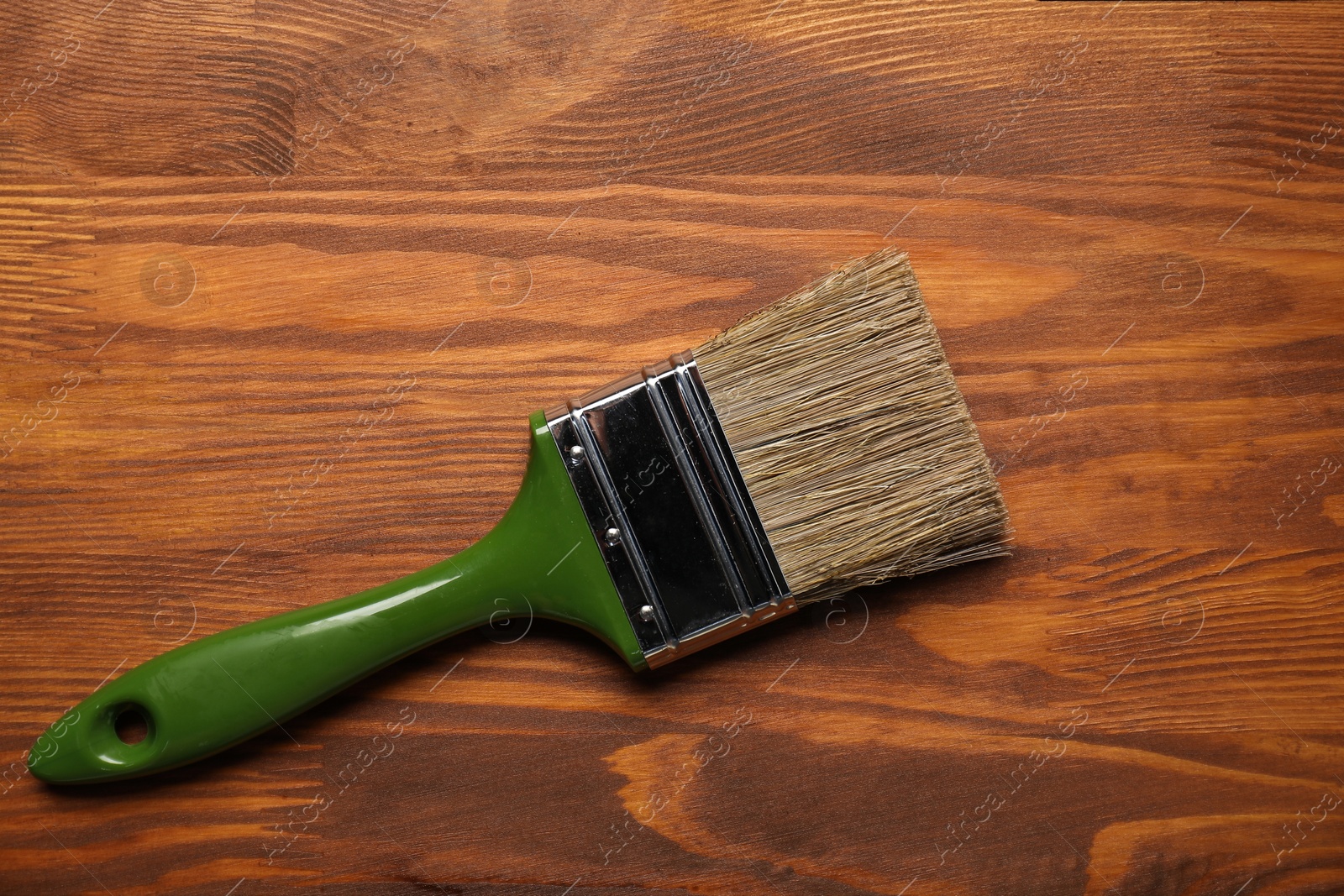 Photo of Applying walnut wood stain. Brush on wooden surface, top view