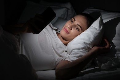 Bad habit. Young woman using smartphone in bed at night