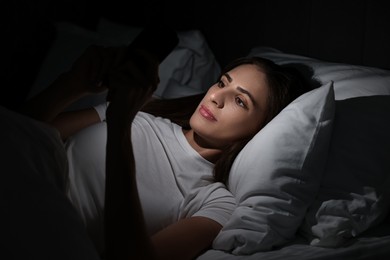 Bad habit. Young woman using smartphone in bed at night