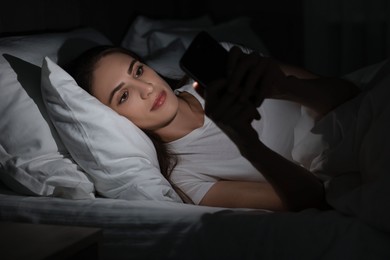 Bad habit. Young woman using smartphone in bed at night