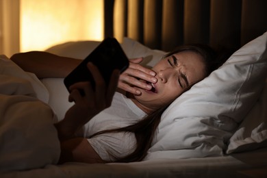 Bad habit. Young woman using smartphone in bed at night