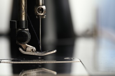 Photo of Professional sewing machine on blurred background, macro view. Space for text