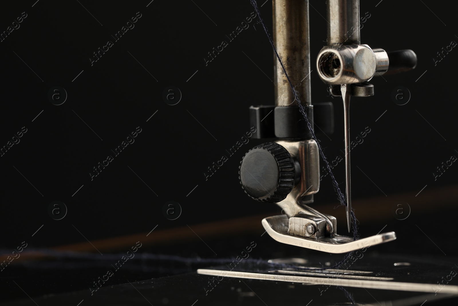 Photo of Professional sewing machine on black background, macro view. Space for text