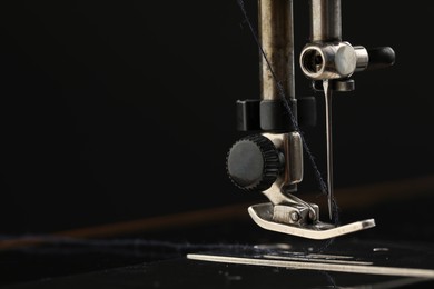 Photo of Professional sewing machine on black background, macro view. Space for text