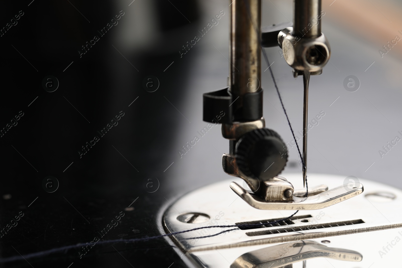 Photo of Professional sewing machine on blurred background, macro view