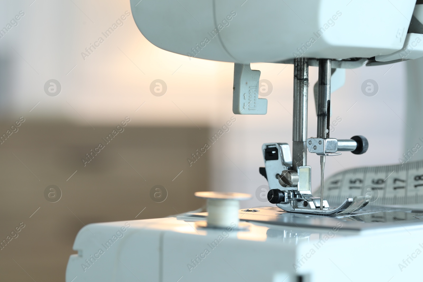 Photo of Sewing machine with thread on blurred background, macro view